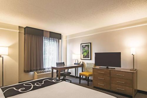 a hotel room with a bed and a desk with a television at La Quinta by Wyndham Oklahoma City Norman in Norman