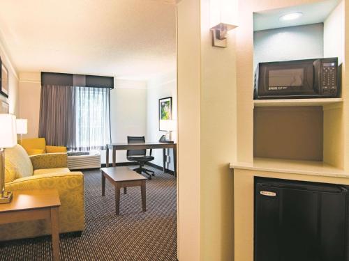 a hotel room with a couch and a table with a tv at La Quinta by Wyndham Oklahoma City Norman in Norman