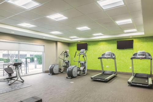 a gym with cardio equipment in a room with a green wall at La Quinta by Wyndham Dallas Plano West in Plano