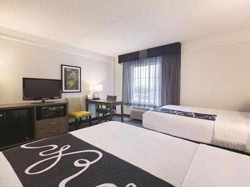 a hotel room with two beds and a flat screen tv at La Quinta by Wyndham Dallas Plano West in Plano