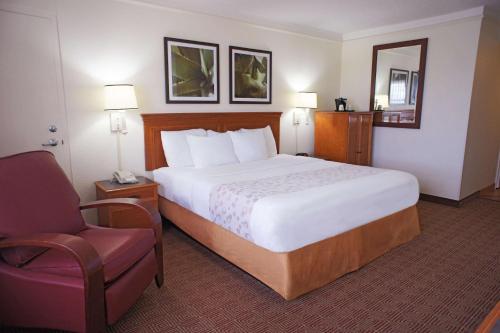コーラルスプリングスにあるLa Quinta by Wyndham Coral Springs University Drの大きなベッドと椅子が備わるホテルルームです。