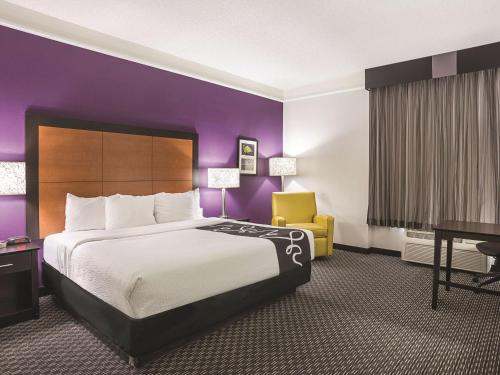 a hotel room with a large bed and a yellow chair at La Quinta by Wyndham Phoenix Scottsdale in Scottsdale