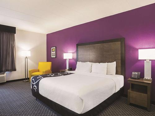 a hotel room with a large bed and a purple wall at La Quinta by Wyndham Atlanta Conyers in Conyers