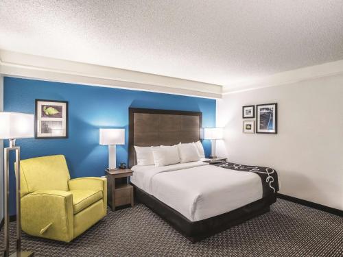 a hotel room with a bed and a yellow chair at La Quinta by Wyndham Phoenix Chandler in Phoenix