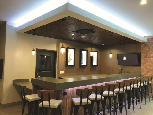 a bar with a bunch of stools in a room at La Quinta by Wyndham New Orleans Downtown in New Orleans