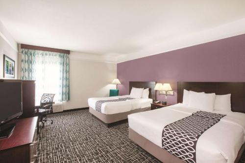 a hotel room with two beds and a flat screen tv at La Quinta by Wyndham Mansfield TX in Mansfield