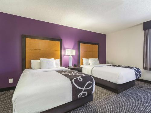 two beds in a hotel room with purple walls at La Quinta by Wyndham Cleveland - Airport North in Cleveland
