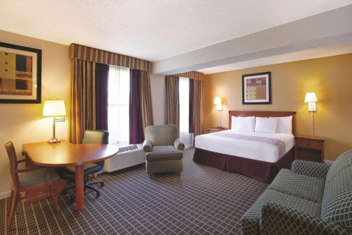 a hotel room with a bed and a desk and chairs at La Quinta Inn by Wyndham Orlando International Drive North in Orlando