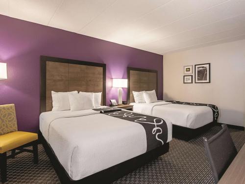 two beds in a hotel room with purple walls at La Quinta Inn & Suites by Wyndham Portland DT Maine Med in Portland