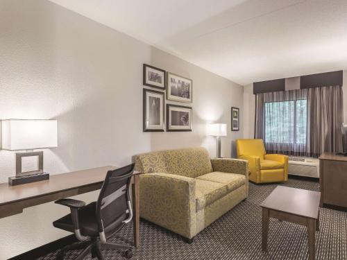a living room with a couch and a desk in a hotel room at La Quinta by Wyndham Columbia / Fort Meade in Jessup
