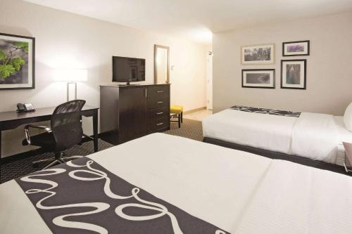 a hotel room with two beds and a desk at La Quinta Inn by Wyndham Oshkosh in Oshkosh