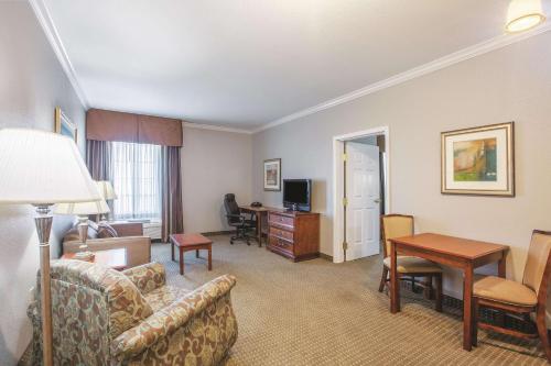 a hotel room with a couch and a table and a desk at La Quinta by Wyndham Gainesville in Gainesville
