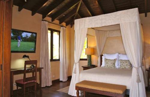 a bedroom with a canopy bed and a television at Royal Isabela in Isabela