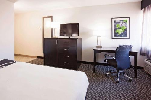 a hotel room with a bed and a desk and a television at La Quinta Inn by Wyndham Oshkosh in Oshkosh