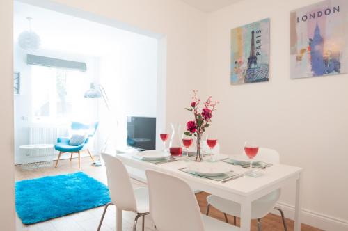 a white dining room with a white table and chairs at The Wellington - Stylish 3-Bedroom House, Sleeps 8, Ideal for Professionals in Burton upon Trent