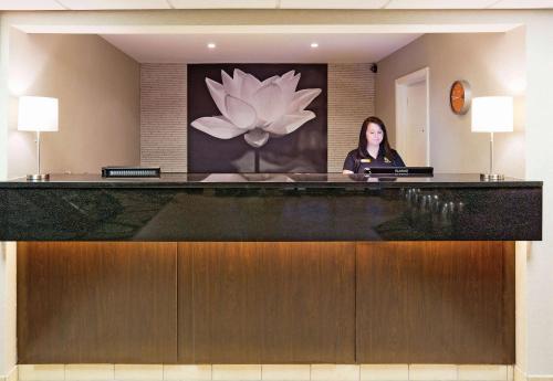 a woman sitting at a reception desk in a lobby at La Quinta Inn by Wyndham Oshkosh in Oshkosh