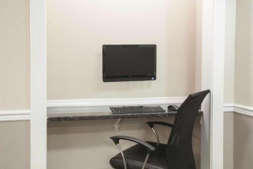 a desk with a computer on a wall with a chair at La Quinta by Wyndham Fort Walton Beach in Fort Walton Beach