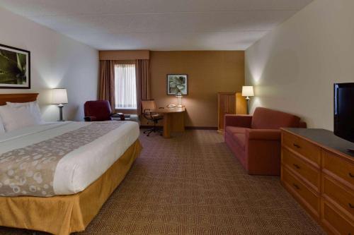 a hotel room with a bed and a couch and a television at La Quinta by Wyndham Lakeland East in Lakeland