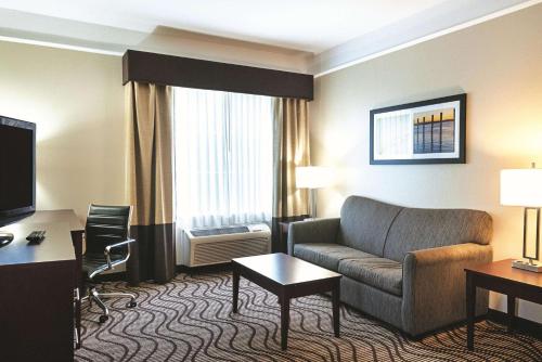 a hotel room with a couch and a desk and a television at La Quinta by Wyndham Houma in Houma