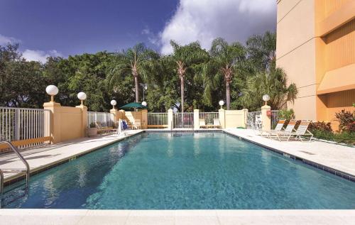 a swimming pool in front of a building with chairs at La Quinta by Wyndham Miami Airport East in Miami