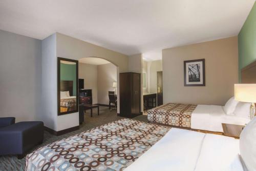 a hotel room with two beds and a living room at La Quinta by Wyndham Knoxville East in Knoxville