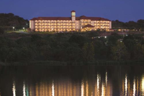 a large building with a clock tower next to a body of water at La Quinta by Wyndham Marble Falls in Marble Falls