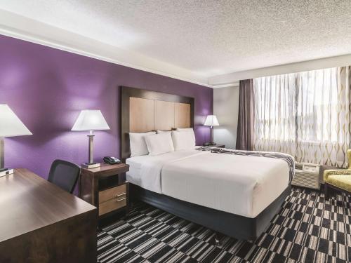 a hotel room with a large bed and purple walls at La Quinta Inn by Wyndham Jupiter in Jupiter