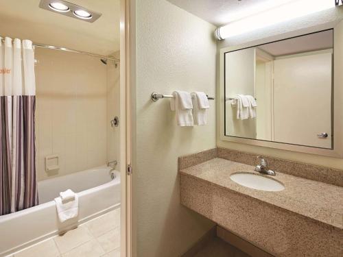 a bathroom with a sink and a tub and a mirror at Mission View Inn & Suites San Diego Sea World - Zoo in San Diego