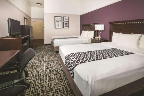 a hotel room with two beds and a flat screen tv at La Quinta by Wyndham Brownwood in Brownwood