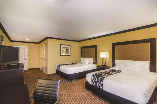a hotel room with two beds and a flat screen tv at La Quinta by Wyndham Brandon Jackson Airport E in Brandon