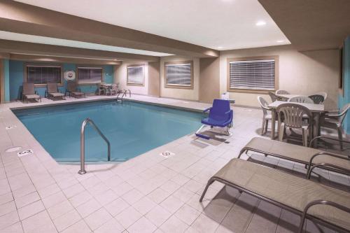 a pool in a hotel room with tables and chairs at La Quinta by Wyndham Erie in Erie