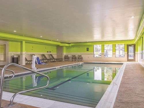 a swimming pool in a building with green walls at La Quinta by Wyndham Cleveland Airport West in North Olmsted