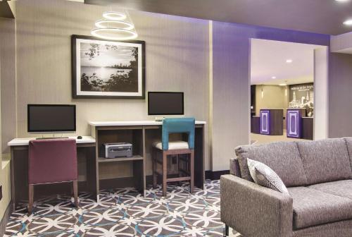 a living room with a couch and a desk with two monitors at La Quinta by Wyndham Cleveland Airport West in North Olmsted