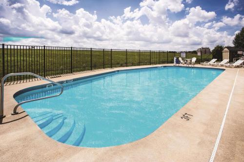 a large swimming pool with a fence and chairs at La Quinta by Wyndham Evansville in Evansville