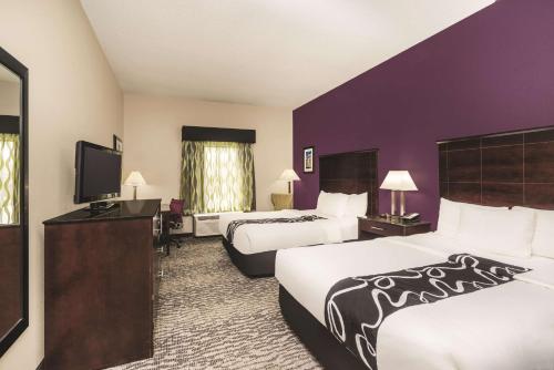 a hotel room with two beds and a flat screen tv at La Quinta Inn & Suites by Wyndham Louisville East in Louisville