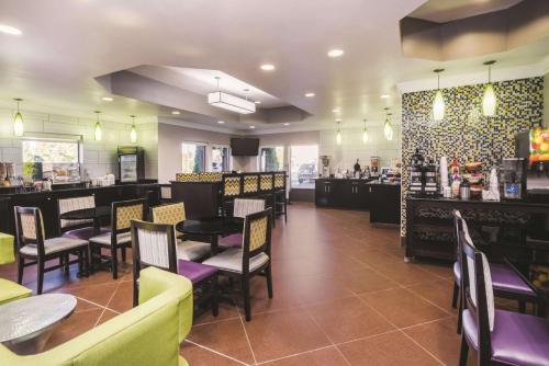 a restaurant with tables and chairs and a bar at La Quinta Inn & Suites by Wyndham Louisville East in Louisville