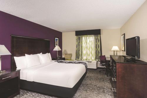 a hotel room with a bed and a flat screen tv at La Quinta Inn & Suites by Wyndham Louisville East in Louisville