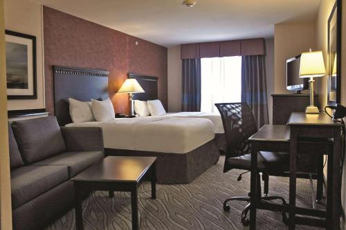 a hotel room with a large bed and a couch at La Quinta by Wyndham Edmond in Edmond