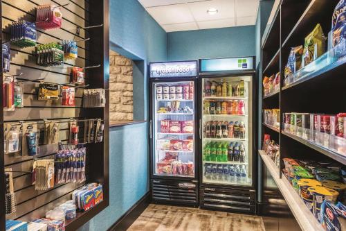 a grocery store aisle with a refrigerator full of drinks at La Quinta by Wyndham Dallas Grand Prairie South in Grand Prairie