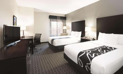 a hotel room with two beds and a flat screen tv at La Quinta by Wyndham Billings in Billings
