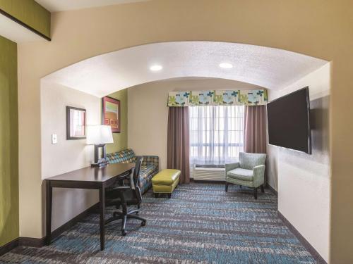 a hotel room with a desk and a tv at La Quinta by Wyndham Dallas Grand Prairie South in Grand Prairie