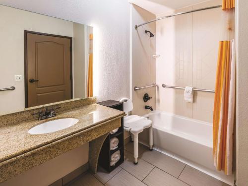 a bathroom with a sink and a tub and a toilet at La Quinta by Wyndham Dallas Grand Prairie South in Grand Prairie