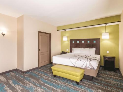 a hotel room with a bed and a yellow stool at La Quinta by Wyndham Dallas Grand Prairie South in Grand Prairie