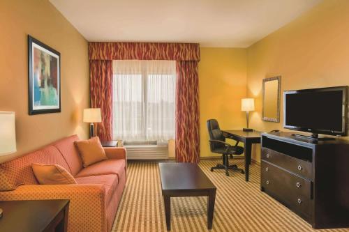 a living room with a couch and a desk with a television at La Quinta by Wyndham Atlanta Union City in Union City