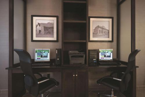 a desk with three computers on it with two chairs at La Quinta by Wyndham Lynchburg at Liberty Univ. in Lynchburg