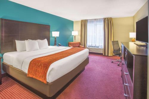 a hotel room with a large bed and a television at La Quinta by Wyndham O'Fallon, IL - St. Louis in O'Fallon