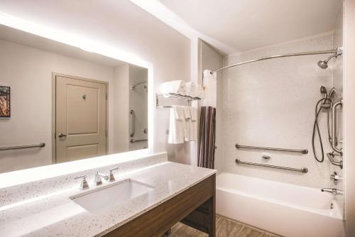 a bathroom with a sink and a tub and a mirror at La Quinta by Wyndham Chambersburg in Chambersburg