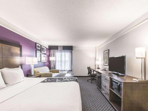 a hotel room with a large bed and a desk at La Quinta by Wyndham Cincinnati Sharonville in Sharonville