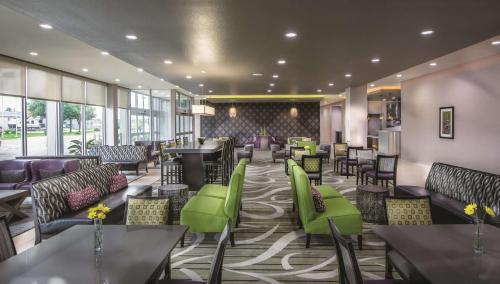 a restaurant with green chairs and tables in a lobby at La Quinta by Wyndham College Station South in College Station