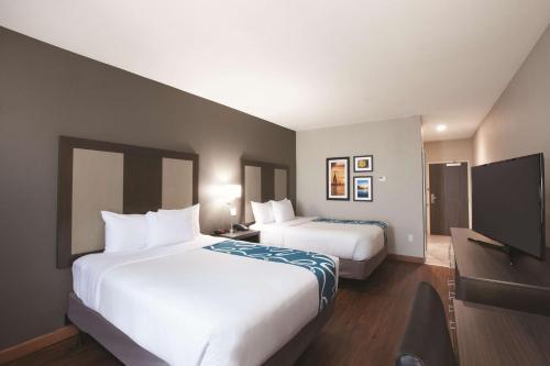 a hotel room with two beds and a flat screen tv at La Quinta by Wyndham Tulsa Broken Arrow in Broken Arrow